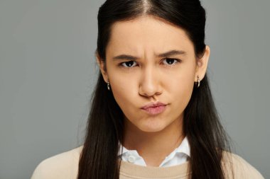 Genç bir kadın, modaya uygun giyinmiş, düşünceli bir ifadeyle bir dizi duygu sergiliyor..