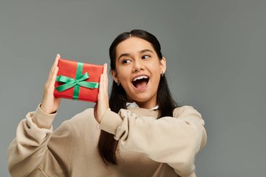 Genç bayan, güzel paketlenmiş bir hediyeyi sergilerken zevk veriyor, heyecan saçıyor..