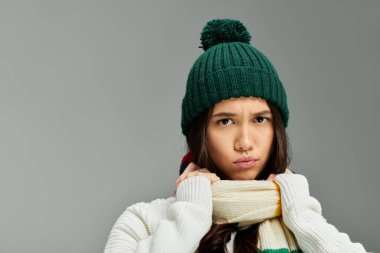 Dressed in fashionable winter wear, a young woman conveys deep emotions with her expression. clipart