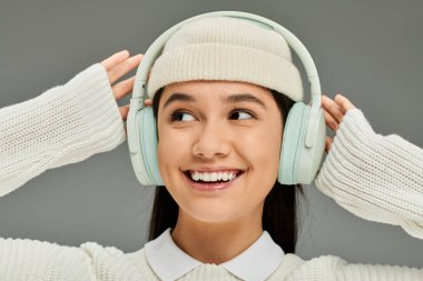 A stylish young woman smiles widely, enjoying her favorite tunes with headphones on. clipart