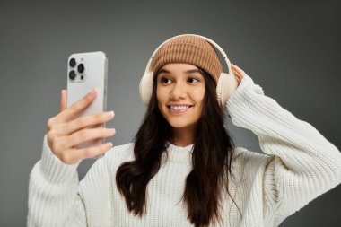 Neşeli bir yüzü olan genç bir kadın müzik dinlerken selfie çekiyor..