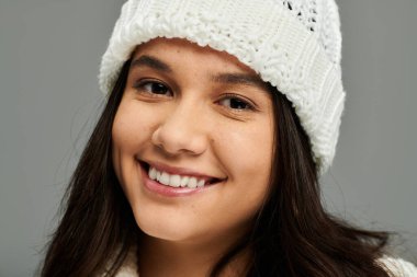 A pretty young woman smiles brightly, expressing joy while dressed in fashionable winter wear. clipart