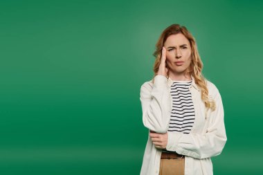 A casual woman with beautiful curly hair stands thoughtfully on a bright green background, lost in her thoughts. clipart