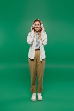 Neşeli bir kadın, kulaklık takıp, rahat bir şekilde müzik dinlemeyi ve gülümsemeyi sever..