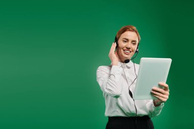Profesyonel giyimli bir kadın müşterileriyle tablet kullanarak etkileşime girer, pozitiflik ve profesyonellik yayar..