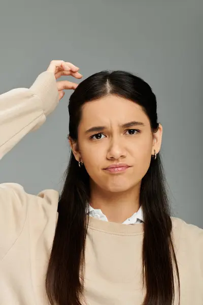 stock image A stylish young woman with long hair shows her emotions while pondering a thought.