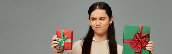 Красивая молодая женщина выражает замешательство, держа в руках два красочных завернутых подарка.