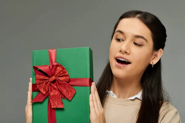 stock image The woman displays delight as she holds a beautifully wrapped present adorned with a bow.