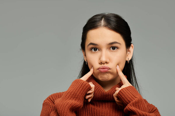 Стильно одетая женщина делает игривое выражение лица, демонстрируя свои яркие эмоции.