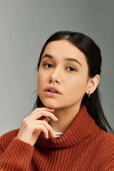 stock image A young woman in a chic sweater conveys deep emotions in a modern indoor environment.