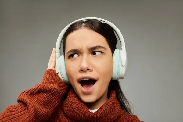 stock image With headphones on, a young woman experiences a burst of emotion as she immerses herself in music.