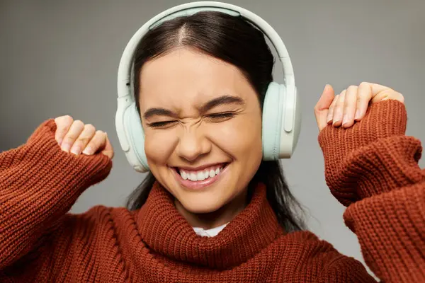 stock image A young woman listens to music with headphones, joyfully expressing her emotions through smiles.