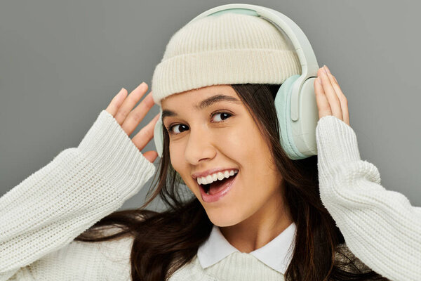 A young woman with a bright smile listens to music, embracing her fashionable style and emotion.