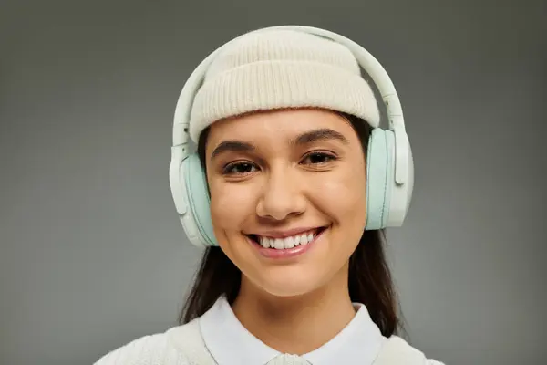 stock image A cheerful young woman with a stylish outfit and headphones beams with emotion in a modern setting.