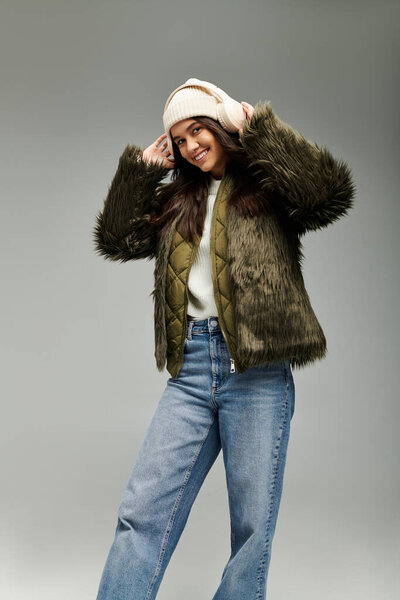 A young woman in trendy winter clothing radiates joy while posing with a charming flair.
