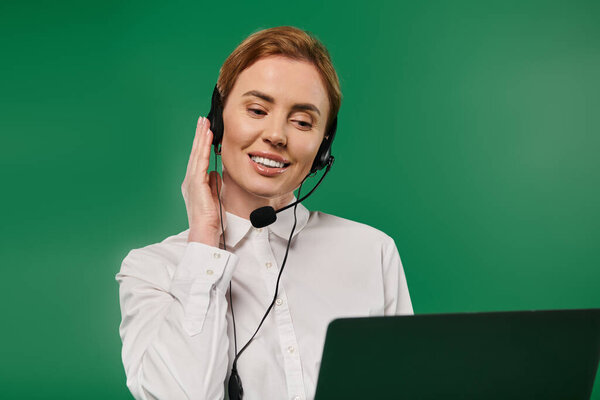 Профессиональная женщина в белой рубашке тепло общается с клиентами на ярком зеленом фоне.