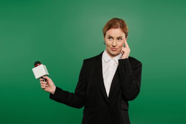 Resmi siyah kıyafetli kendinden emin bir TV sunucusu açık yeşil bir arkaplanda dururken etkin bir şekilde iletişim kuruyor..