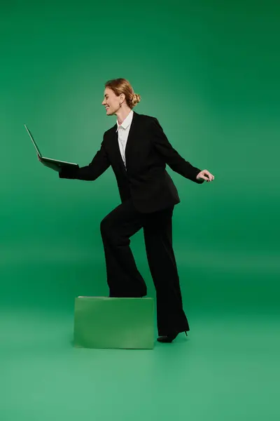 stock image A poised presenter stands confidently on a platform while interacting with a laptop, showcasing professionalism.