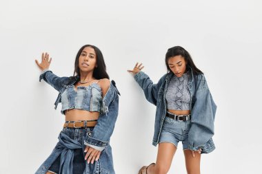 Genç bir kadın, modaya uygun kot elbiselerle, şık bir şekilde poz veriyor..