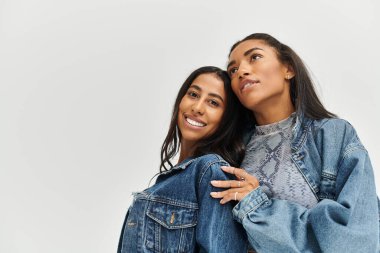 Şık giyimli genç kadınlar moda anlayışlarını neşeli pozlar ve gülümsemelerle sergilerler..