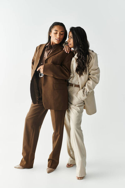 Две молодые женщины, одетые в элегантные наряды, уверенно позируют, демонстрируя свое уникальное чувство стиля.