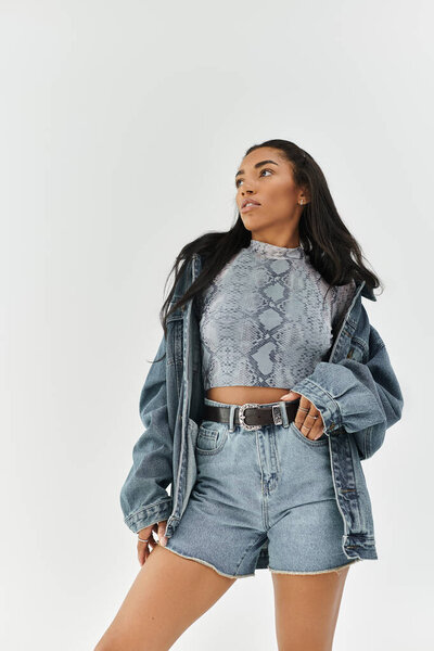 A young woman confidently models trendy denim shorts, a chic top, and cowboy boots, exuding style.