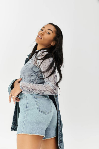 Модная молодая женщина с уверенностью демонстрирует свой уникальный стиль денима в современной обстановке.