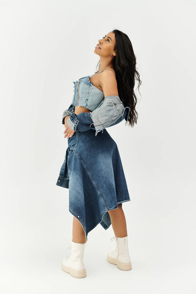A fashionable young woman dressed in chic denim looks up thoughtfully, radiating elegance and poise.