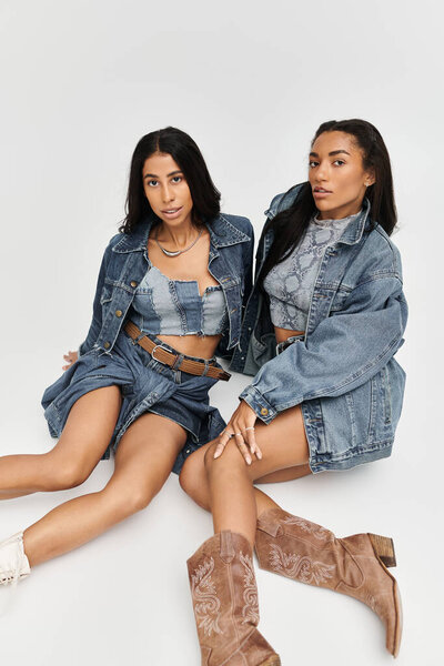 Две молодые женщины элегантно позируют в модных джинсовых ансамблях, излучая уверенность и стиль.