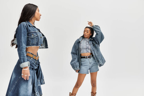 Молодая женщина выражает уверенность в себе, надевая модный джинсовый наряд в шикарной обстановке.