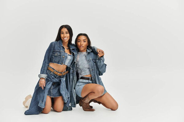 Две красивые молодые женщины демонстрируют модные джинсовые взгляды, выражая уверенность и творчество.