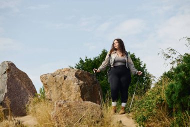 Büyük beden bir kadın güzel bir tarlada güvenle duruyor, doğal ortamın tadını çıkarıyor..