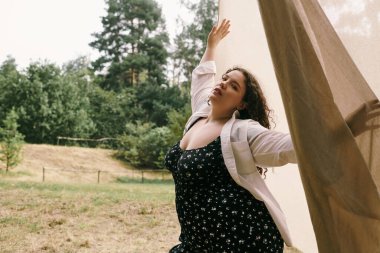 Kendinden emin ve iri bir kadın güneşli bir alanda dans ederken doğayı kucaklar..