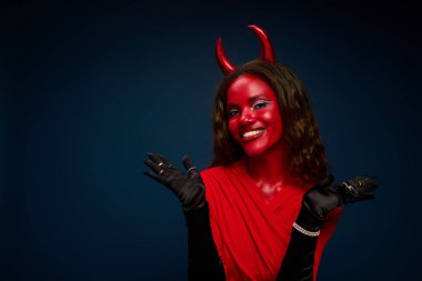 A stunning woman in a bright red devil costume radiates Halloween joy and playful spirit. clipart