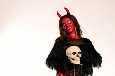 A beautiful woman embodies a devilish character, executing a captivating pose with a skull. clipart