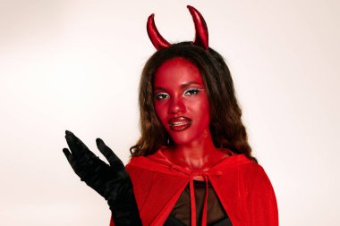 A striking woman in a devil costume embraces the Halloween spirit at a lively gathering. clipart