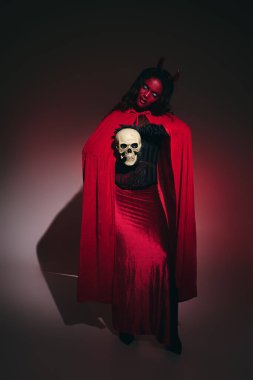 Göz alıcı bir kadın, çarpıcı bir kafatası aksesuarıyla Cadılar Bayramı kostümünü sergiliyor..