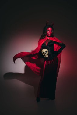 Canlı bir cadılar bayramı kıyafeti giyen bir kadın, yaratıcı bir şekilde kostümünü göstererek.