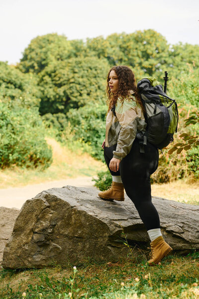 A plus size woman takes a bold step forward on a rocky path through a vibrant green forest.
