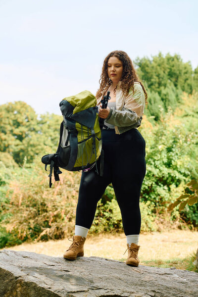 A confident plus size woman stands amid lush greenery, getting ready for an outdoor adventure.
