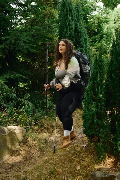 stock image A confident woman embraces nature while hiking peacefully through vibrant greenery.