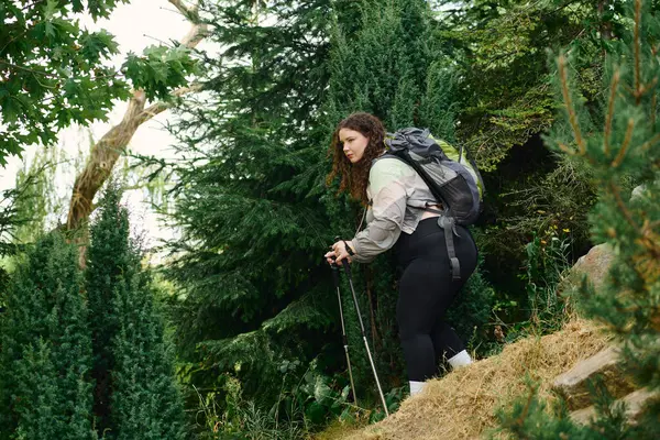 stock image A beautiful plus size woman navigates through lush greenery, embracing the tranquility of nature.