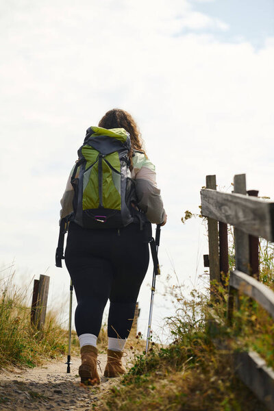 A confident woman explores a vibrant field, enjoying the warmth of the sun and natures wonders.