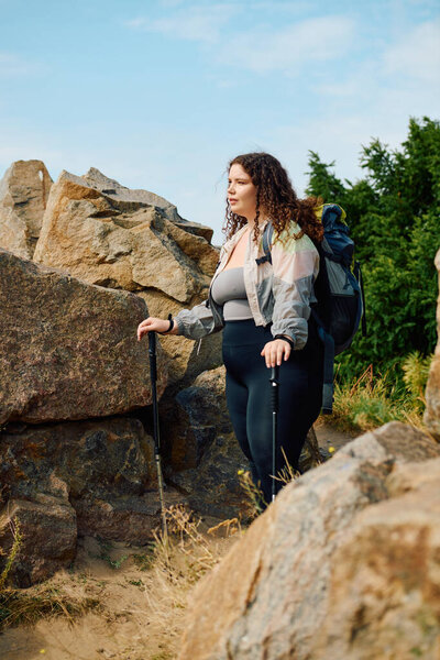Принимая красоту природы, плюс размер женщина уверенно прогулки по скалистой местности.