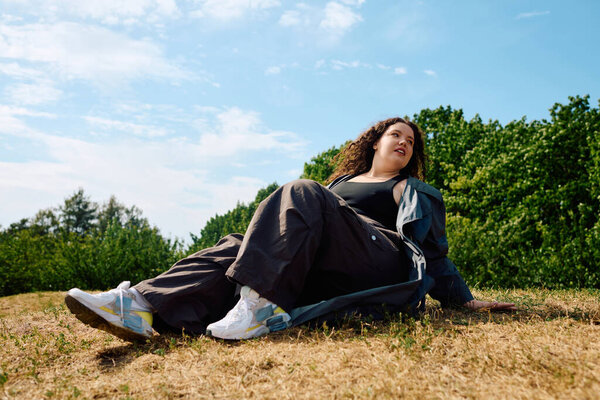 A joyful woman relaxes in a sunlit field, surrounded by lush greenery and clear skies.
