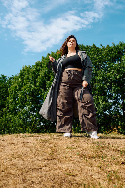 A stylish plus size woman poses confidently amidst lush greenery, embracing her unique beauty.
