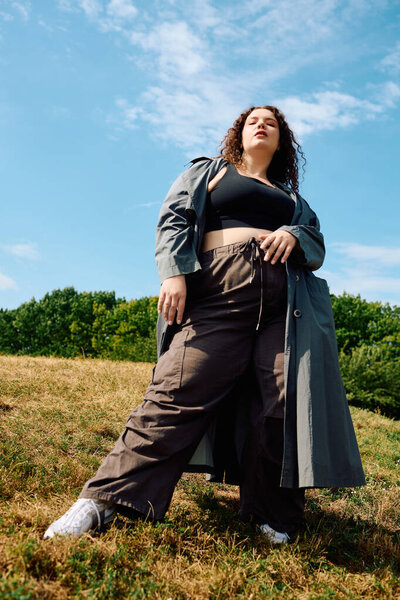 Великолепная женщина plus size гордо стоит в пышном поле, купаясь в теплом сиянии.