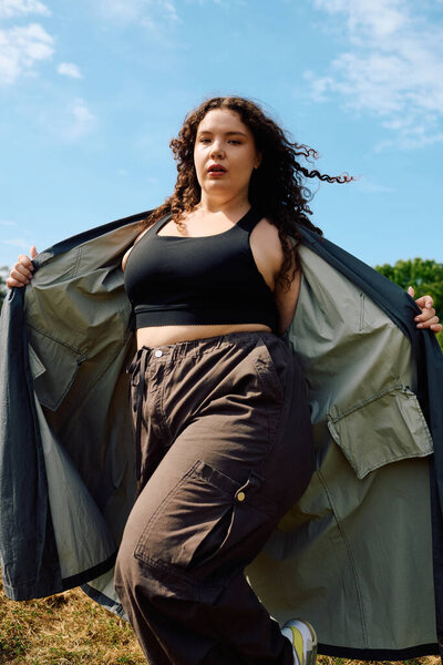 A confident plus size woman revels in the beauty of a sunlit field, surrounded by nature.