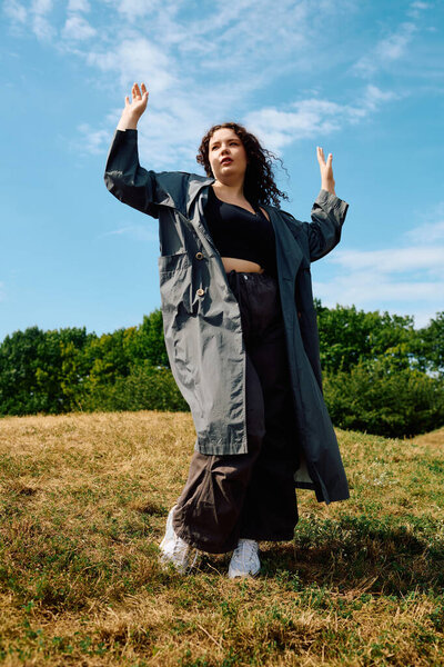 A confident woman embraces nature, dancing with joy in an open field under sunny skies.