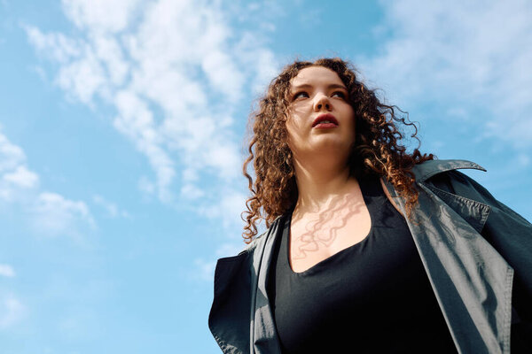 В пышном поле, уверенная в себе плюс размер женщина наслаждается красотой природы под ярким небом.